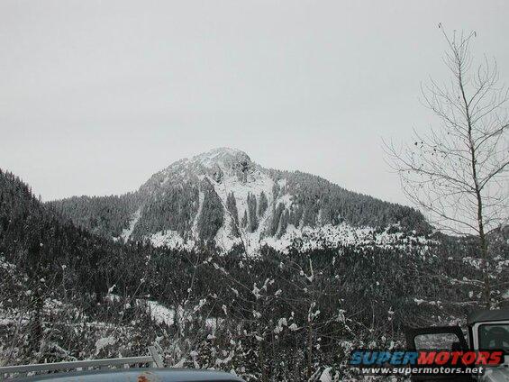 Snowy mountain landscape with a vehicle in the foreground.