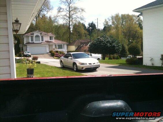 Silver 2002 Pontiac Grand Prix in a driveway, viewed from a pickup truck bed.