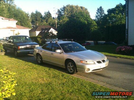 Silver 2002 Pontiac Grand Prix sedan with roof rack parked on street.