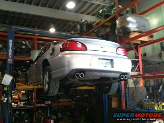 Silver Pontiac Grand Prix on a car lift, rear view.