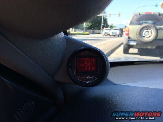 Digital gauge showing coolant and transmission temperatures inside a vehicle.
