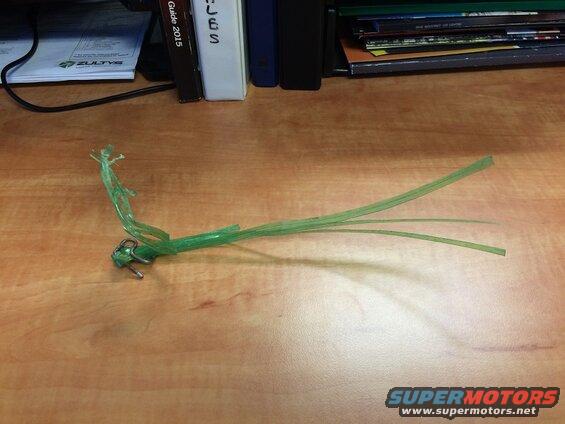 Broken green plastic zip tie with metal lock on a wooden desk
