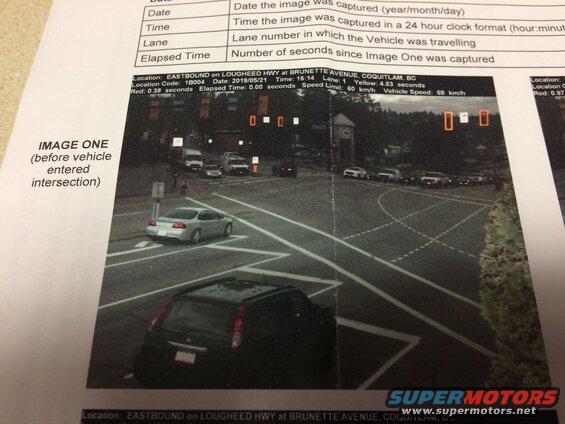 Silver 2002 Pontiac Grand Prix driving through an intersection, with a black SUV in the foreground.