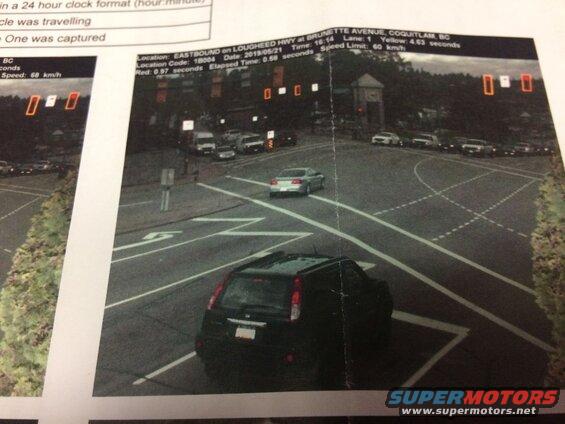 Black SUV at intersection with traffic camera document overlay showing speed and violation.
