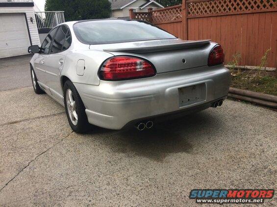 Silver 2002 Pontiac Grand Prix rear view with spoiler and dual exhaust.