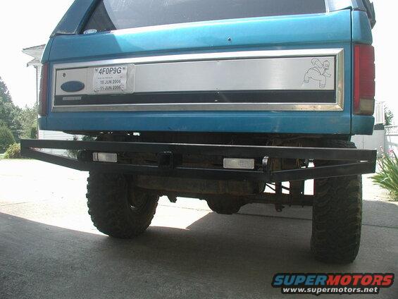 Rear view of a teal SUV with custom bumper and Homer Simpson sticker.