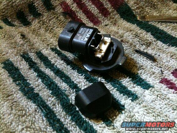 Disassembled PIAA headlight bulb socket assembly on a striped towel.