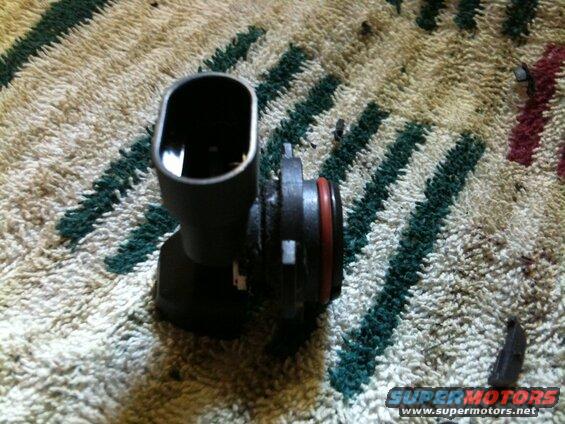 Black automotive part with red O-ring on striped carpet