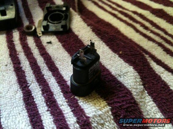 Black PIAA relay with metal prongs on a striped towel.