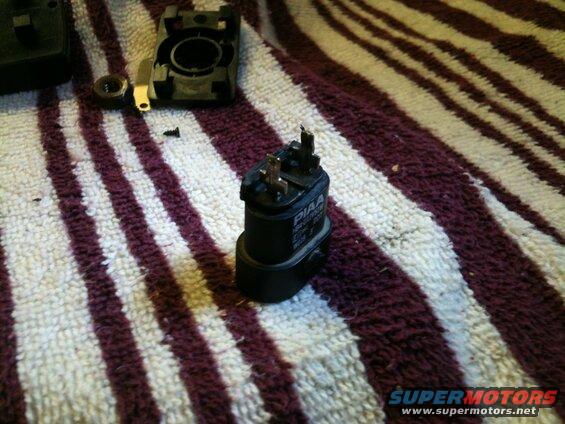 Close-up of a black PIAA automotive relay on a striped towel.