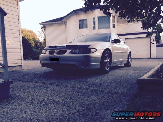 Silver 2002 Pontiac Grand Prix with aftermarket wheels and bug deflector parked in driveway.