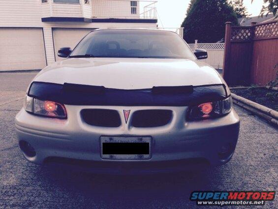 Silver 2002 Pontiac Grand Prix front view with black car bra and orange headlights.