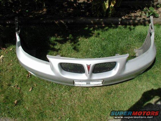 Silver Pontiac Grand Prix front bumper cover with black mesh grille and red emblem