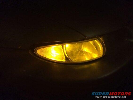 Close-up of a yellow car headlight with textured and faceted lenses.