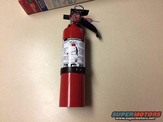 Red fire extinguisher with instructions on a table.