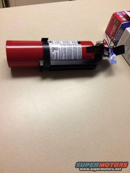 Red fire extinguisher on a light-colored surface with a partial cardboard box.