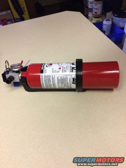 Red fire extinguisher with instructions on a black bracket.
