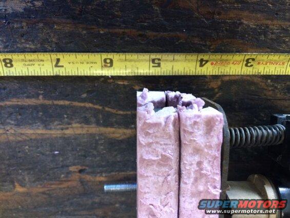 Yellow measuring tape and pink fibrous material in a vise.