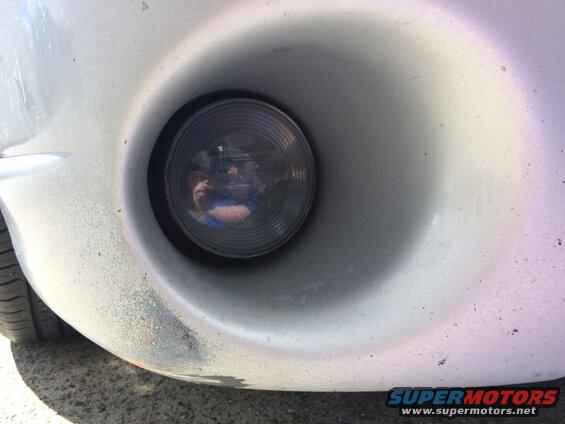 Driver's side fog light and scuffed bumper on a silver 2002 Pontiac Grand Prix.