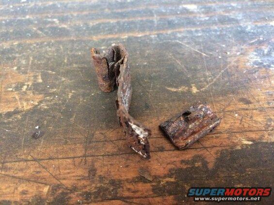 Two rusted metal fragments on a wooden surface.
