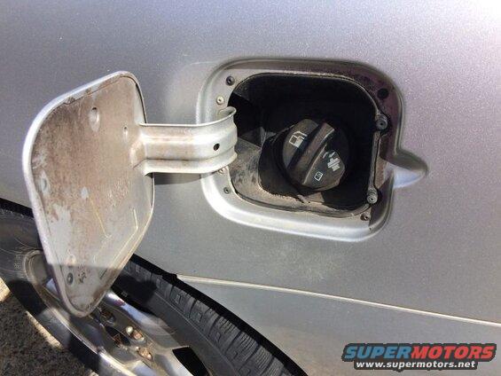 Open fuel filler door on a silver car, showing the gas cap.
