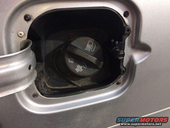 Close-up of a silver car's fuel filler door with gas cap.