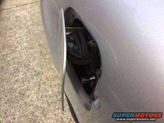 Open fuel filler door on a silver car, showing the gas cap.