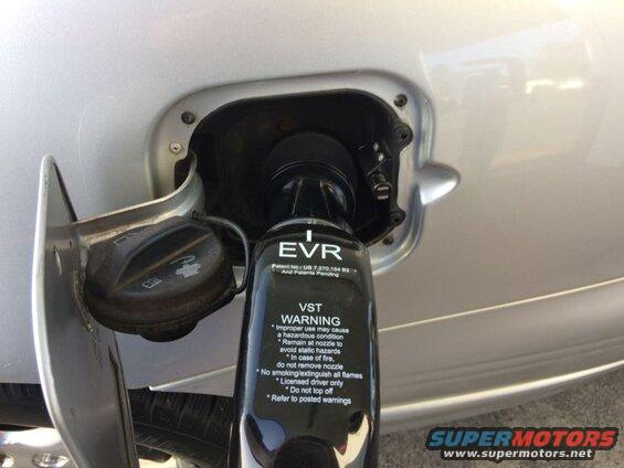 Silver car's fuel filler neck with a black EVR fuel nozzle inserted.