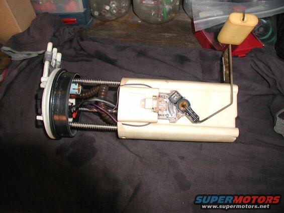 Disassembled fuel pump assembly with float sender on dark cloth