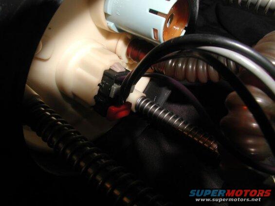 Close-up of a fuel pump housing with electrical connectors and hoses.