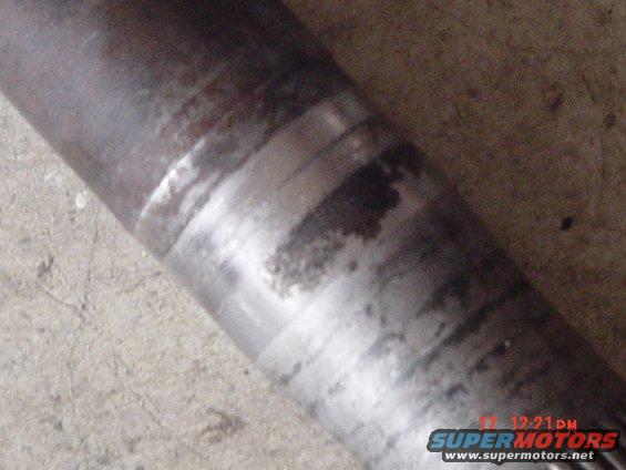 Close-up of a metal shaft showing wear bands and dark stains. Watermark reads SUPERMOTORS