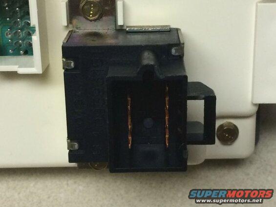 Black electrical connector with copper terminals on white housing, text visible on connector.