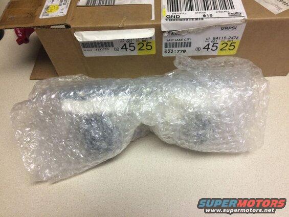 Car part wrapped in bubble wrap on a counter, with a shipping box behind it.