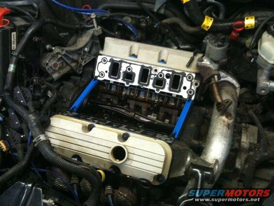Close-up of a car engine with intake manifold removed, showing camshafts and valves.