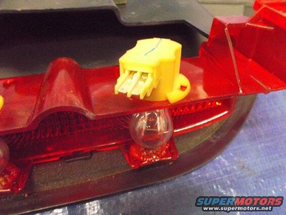 Close-up of a red taillight assembly with a clear bulb and yellow connector.
