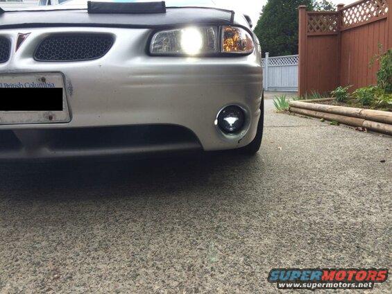 Silver Pontiac Grand Prix front bumper with illuminated headlights and fog light.
