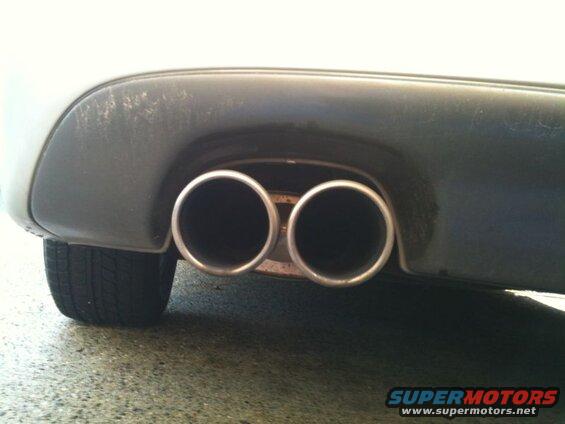 Close-up of a car's dual exhaust pipes and rear bumper.
