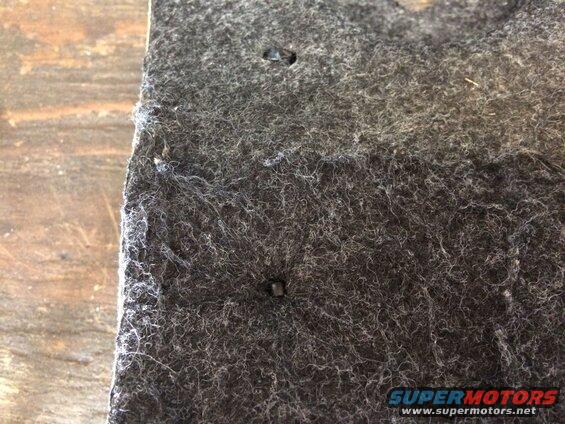 Close-up of dark gray felt material with two metal fasteners.