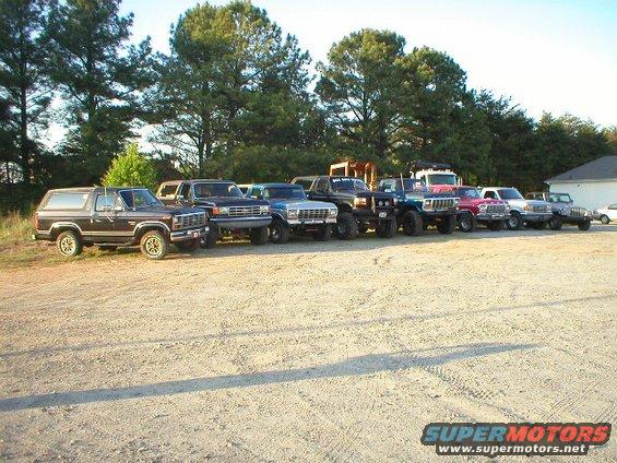 1989 Ford Bronco and other SUVs parked in a line on a gravel lot