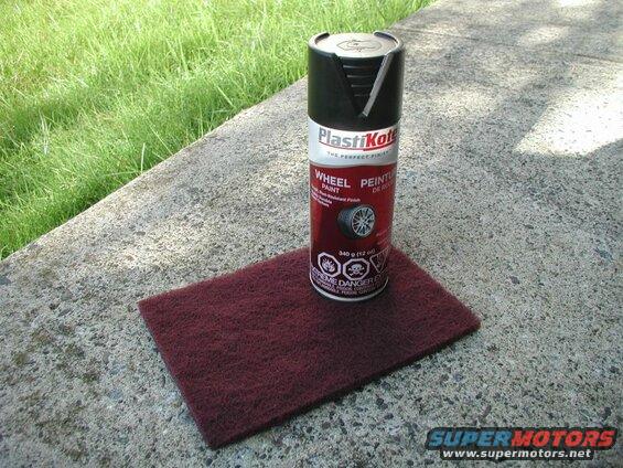 Can of PlastiKote wheel paint and maroon abrasive pad on concrete ledge.