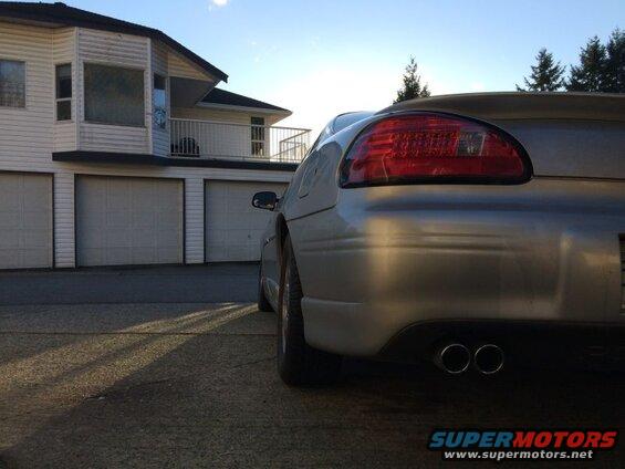 Rear driver's side of a silver 2002 Pontiac Grand Prix with dual exhaust pipes and spoiler.