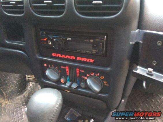 Car dashboard with JVC stereo, climate controls, and "GRAND PRIX" lettering.