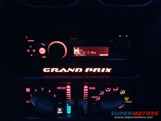 Illuminated dashboard of a Pontiac Grand Prix at night, showing the radio and climate controls.