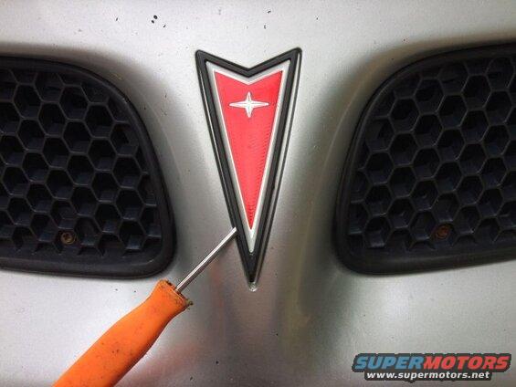 Use a small flathead screwdriver and gently pry up the old emblem.