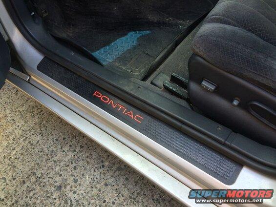Interior door sill with red "PONTIAC" lettering and textured black strip.