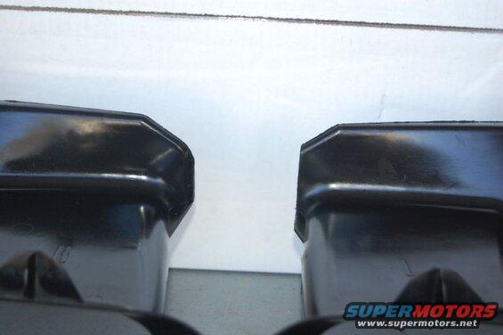 Two black plastic car parts with angled edges, viewed from below.
