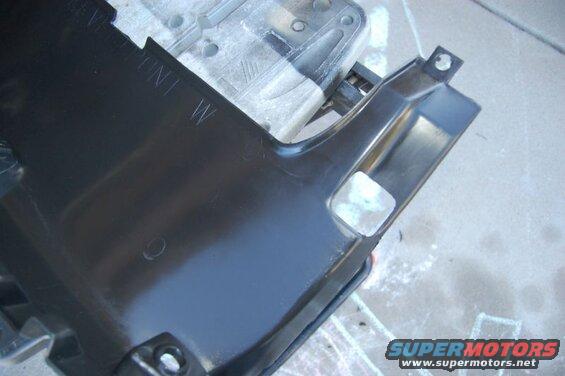 Black plastic car part with embossed text "VE FRONT W" and cut-out sections.