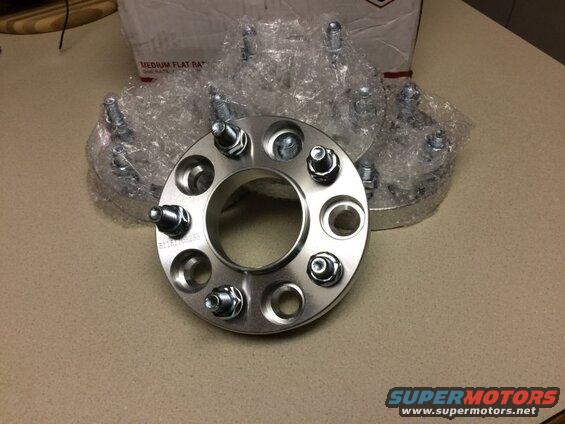 Four wheel spacers with bolts, one in focus with part number visible.