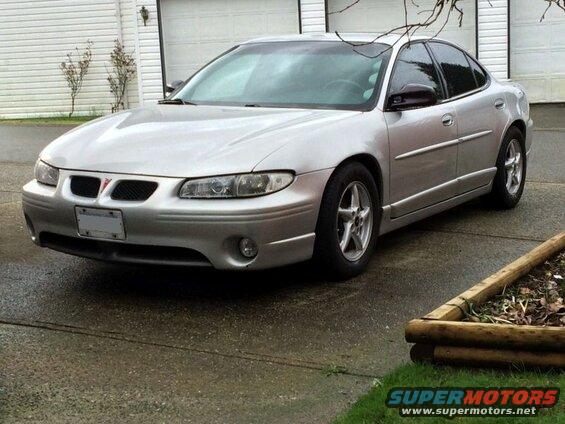 Silver 2002 Pontiac Grand Prix sedan parked on a wet driveway.