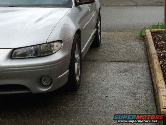 Silver sedan parked on wet concrete driveway, front passenger side view.